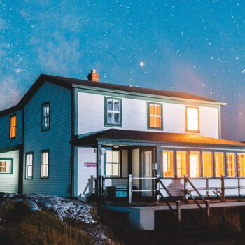 wooden house on a hill under a starry blue night sky