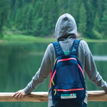 person wearing grey hoodie looking at lake