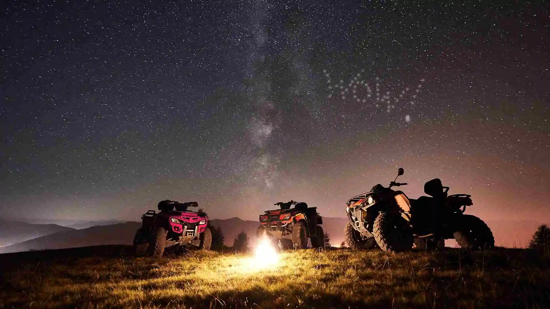 three atvs around a campfire at night