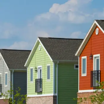 Four colorful houses in a row against a blue sky.