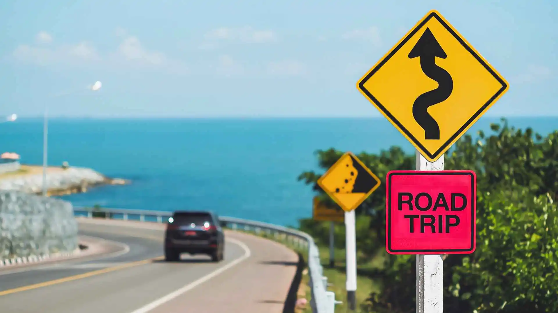 car driving on highway past road trip sign