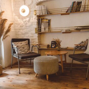 Armchair with table and ottoman in a bright room with white painted brick walls