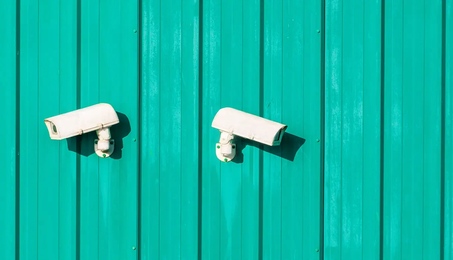 White security cameras on paneled wall.