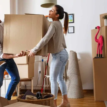 young couple lifting moving boxes in new apartment