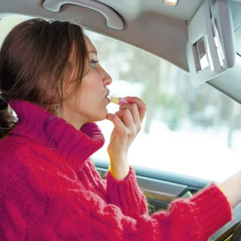 female driver applying lip balm behind the wheel