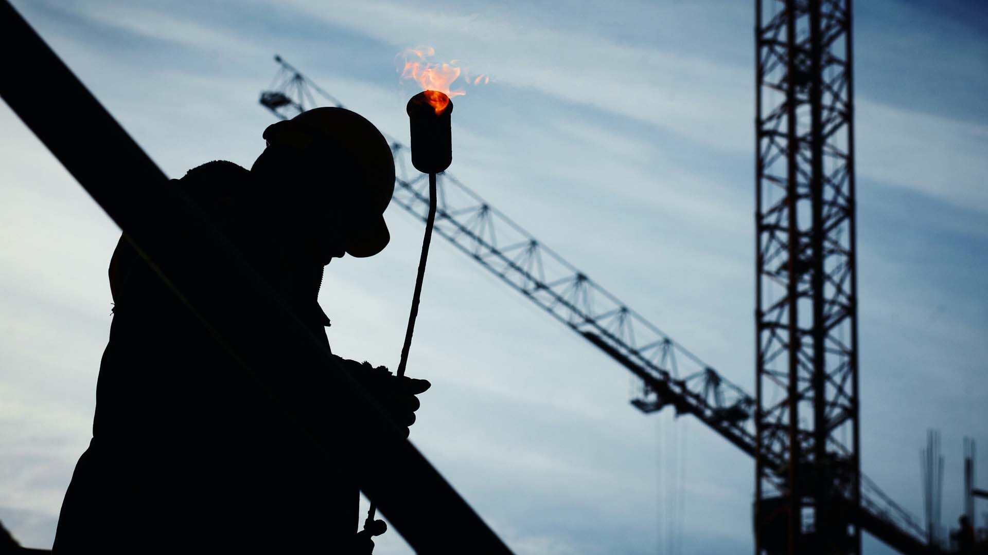 Construction worker on site carrying a blowtorch