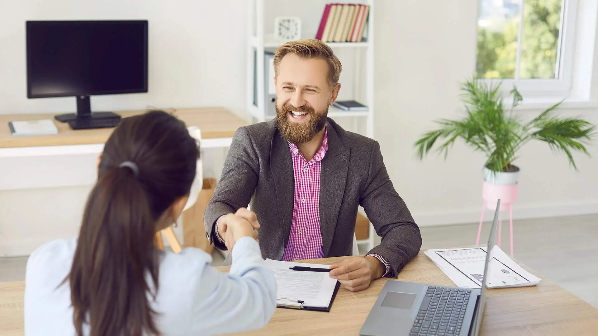 two people in a meeting shaking hands smiling