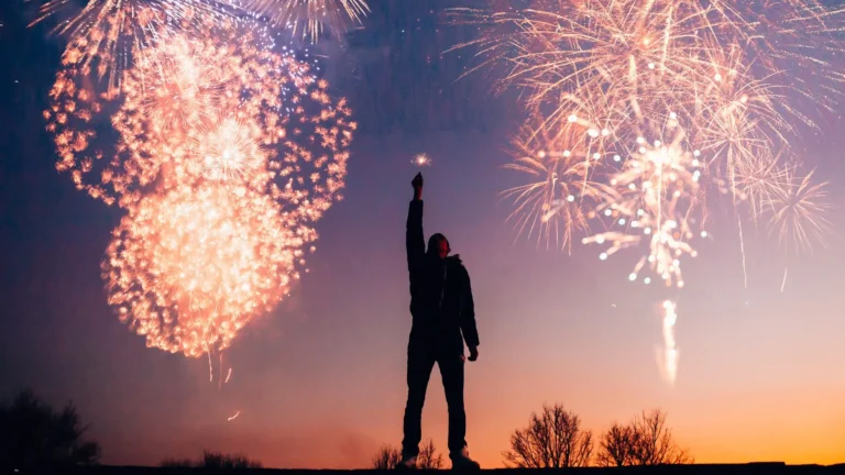 person raising arm with fireworks in the background