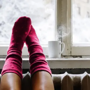 Person getting warm by the window heater.