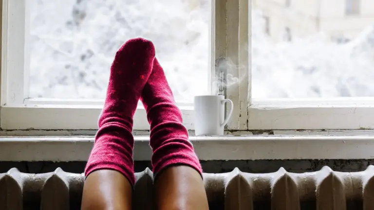 Person getting warm by the window heater.