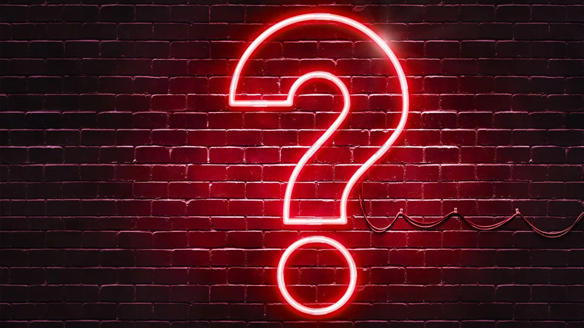 pink lit neon question mark sign on brick wall