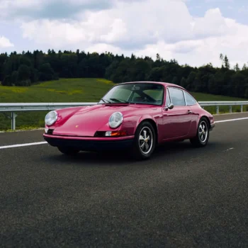 Classic car driving on road.