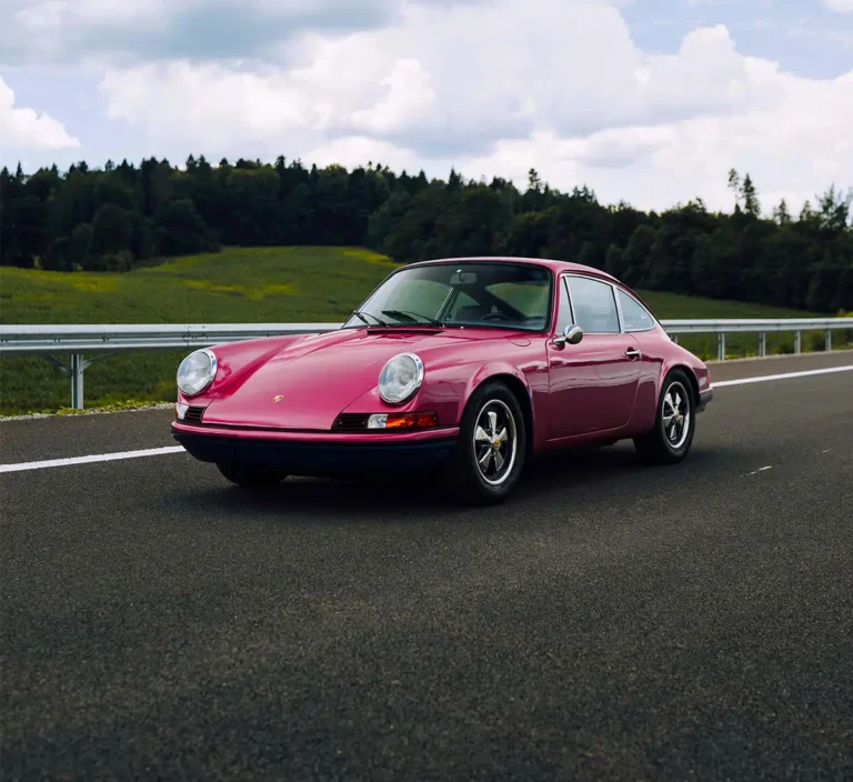 Classic car driving on road.