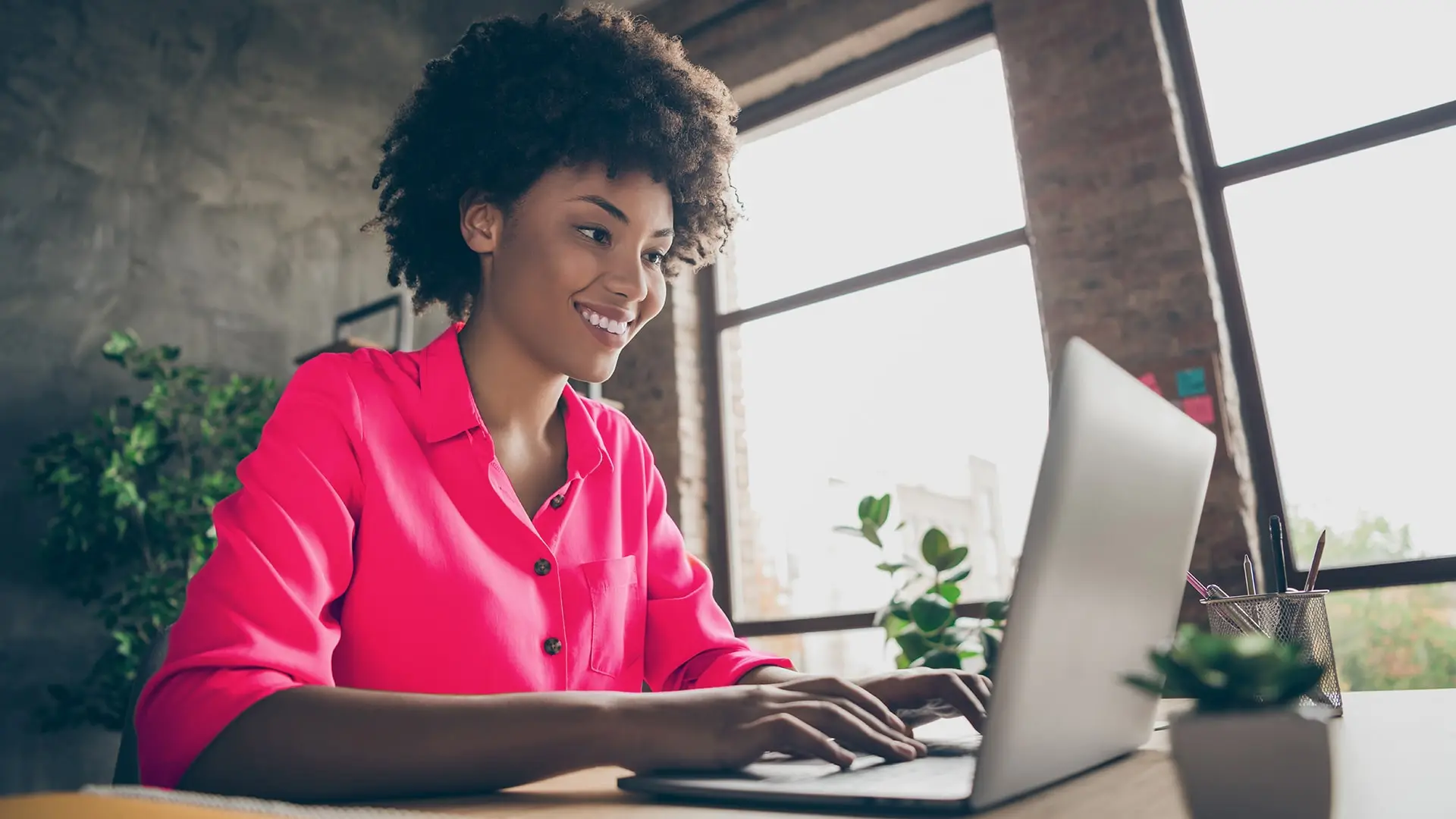 woman sitting in front of laptop reviewing file smiling