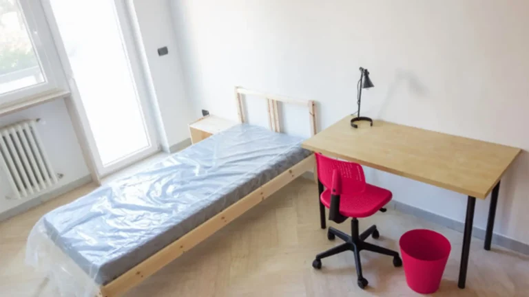 student dorm room with empty bed and desk