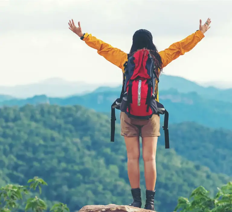 Woman standing on trail wearing backpack.