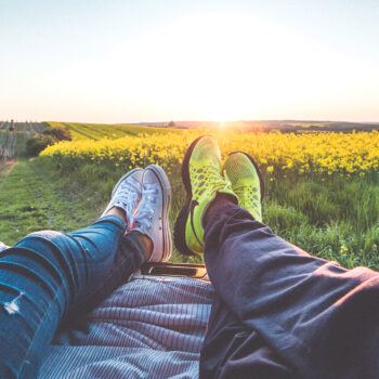 people looking at yellow field with feet up