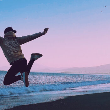 Person jumping on a beach in the sunset.