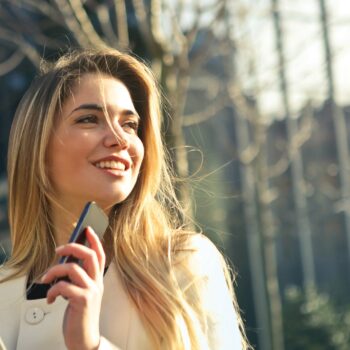 Woman holding smartphone and tablet sitting outside.