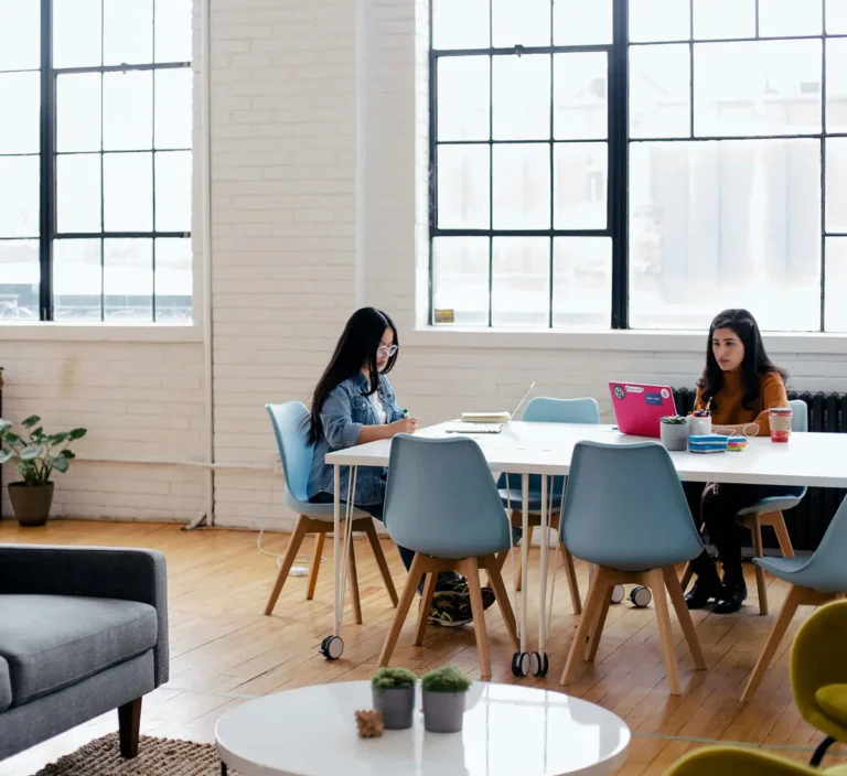 Two people working at a desk in an office.