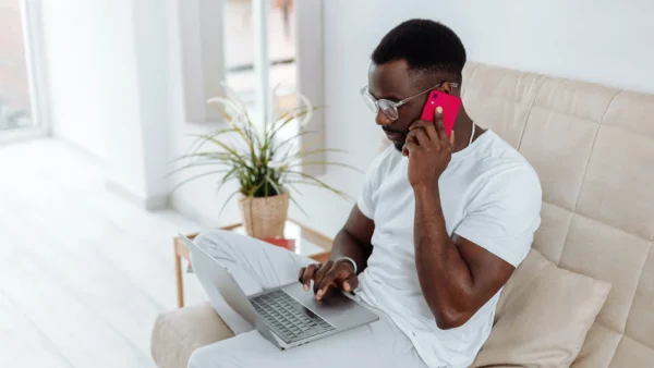 man using phone with laptop on lap