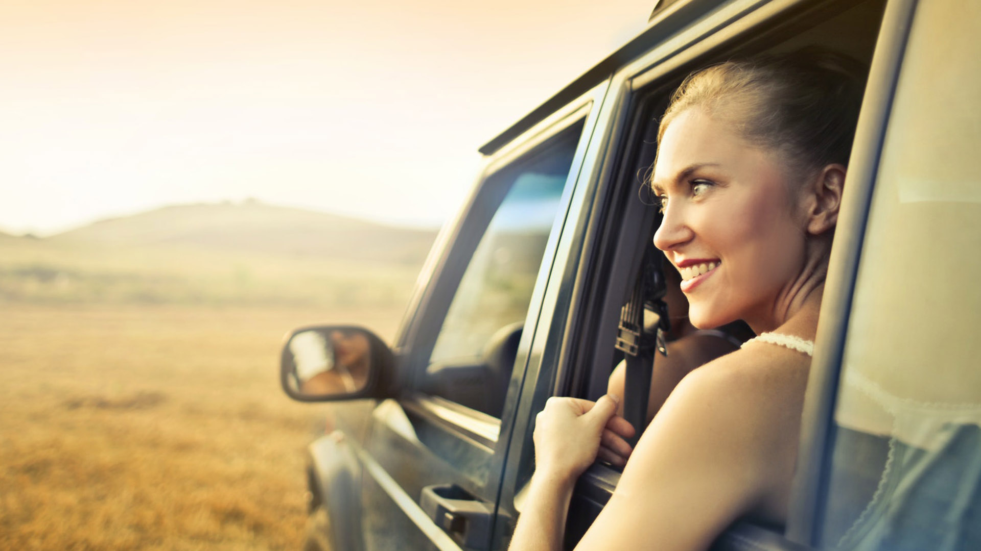 woman leaning out back seat window of vehicle