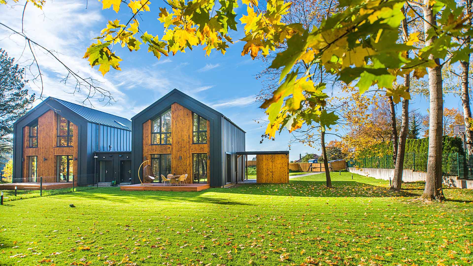 Twin houses of wood and black metal with a large front lawn