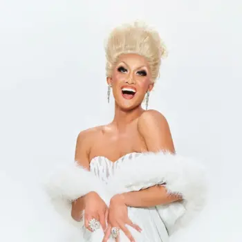 Kyne smiling in a white sequin dress and white boa.