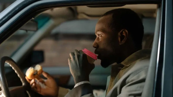 driver drinking coffee with pink lid while eating donut