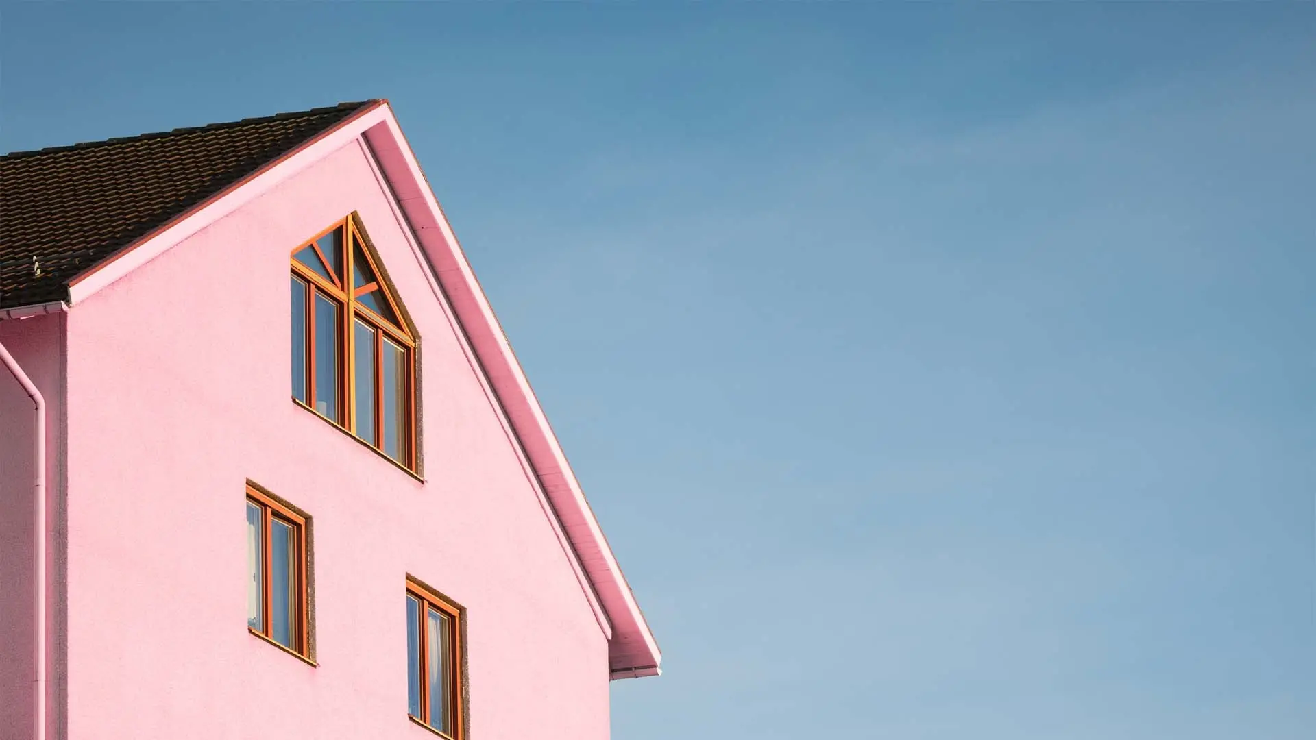 Tall pink house against a clear blue sky.