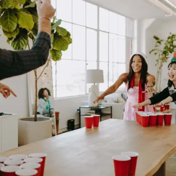 A group of coworkers at a holiday party playing beer pong.