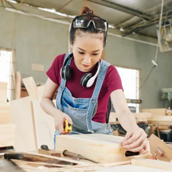 Handyperson in a workshop measuring a wooden drawer.