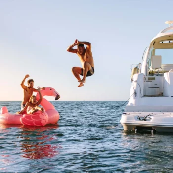 Person jumping into the water from a boat with a group of friends.