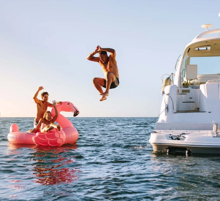 Person jumping into the water from a boat with a group of friends.