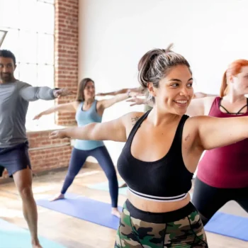 Yoga teacher leading a class in a bright studio.