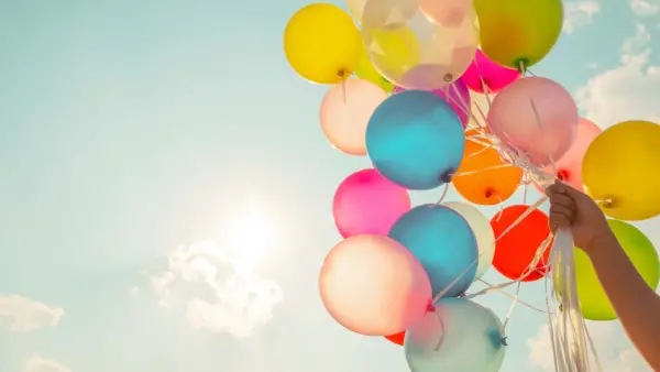 Holding a bunch of balloons in the sky.