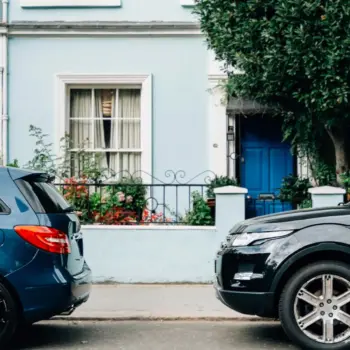 Two cars parked in front of a house.