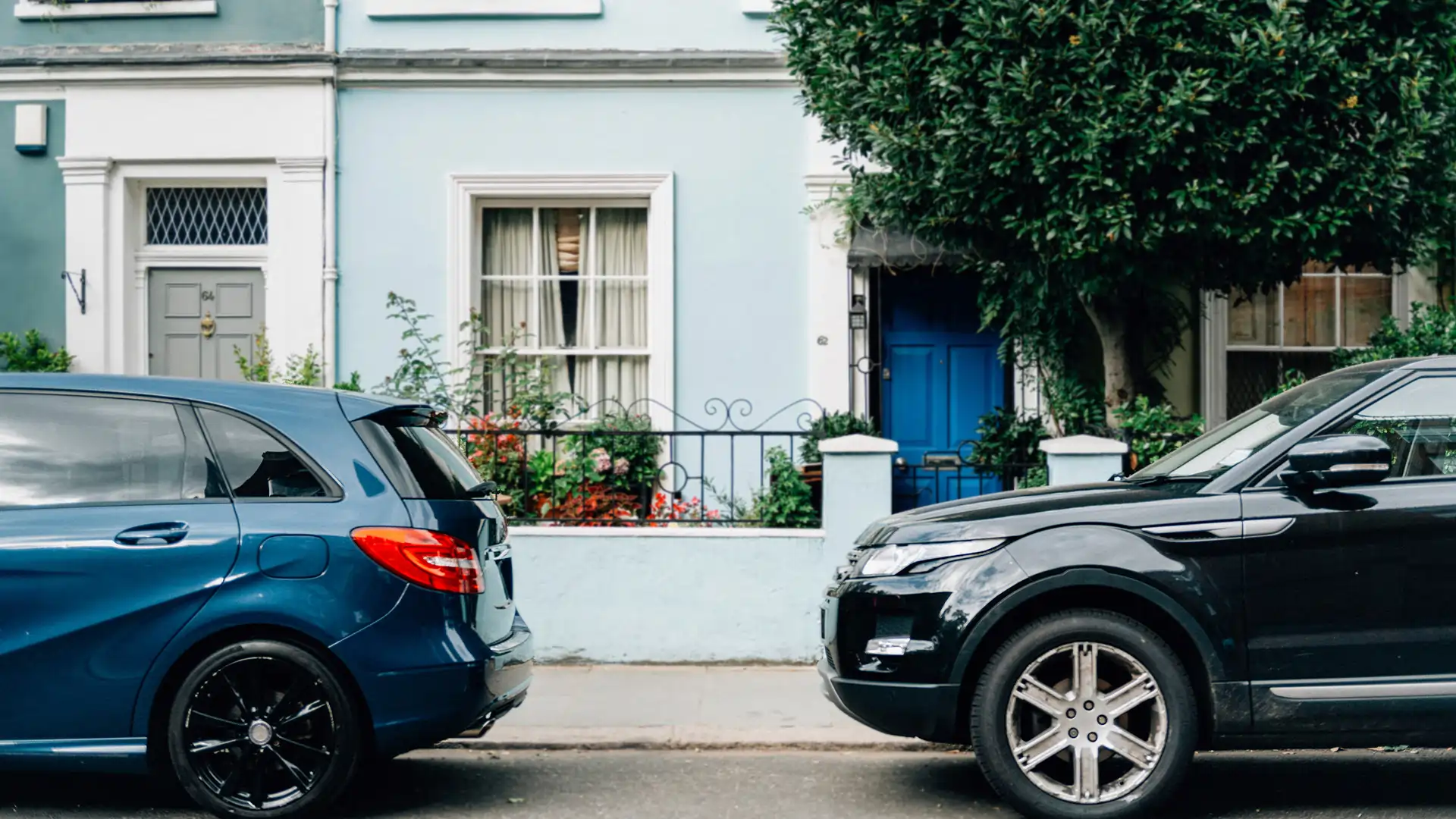 Two cars parked in front of a house.