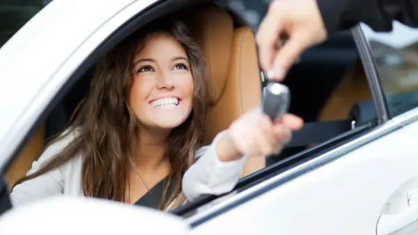 Happy woman getting the keys to her first car.